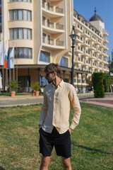 A European-looking man wearing an orange shirt and sunglasses. A tropical country in the hot summer. 