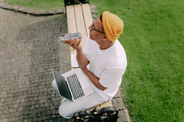 Young African American student sitting and studying in the campus talking on the phone with a smile.