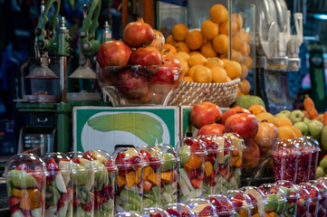 Fruits are harvested and stacked on the counter in the market for squeezing juice on a manual press. Assorted fruit pieces in a transparent glass.