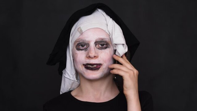 cheerful caucasian boy 7-8 years old in costume and zombie grimme congratulates on the phone on Halloween.children traditional holidays.studio shooting.congratulations on halloween