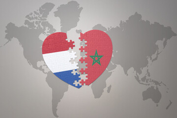 puzzle heart with the national flag of morocco and netherlands on a world map background.Concept.