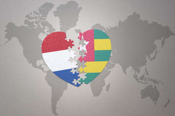 puzzle heart with the national flag of togo and netherlands on a world map background.Concept.