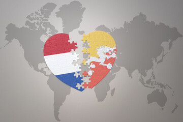 puzzle heart with the national flag of bhutan and netherlands on a world map background.Concept.