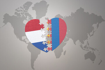 puzzle heart with the national flag of mongolia and netherlands on a world map background.Concept.