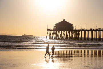 Couple Walking on Beach in Front of the Pier at Huntington Beach California at Sunset