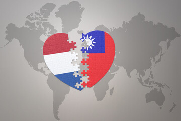 Fototapeta premium puzzle heart with the national flag of taiwan and netherlands on a world map background.Concept.