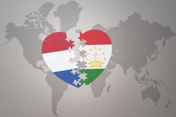 puzzle heart with the national flag of tajikistan and netherlands on a world map background.Concept.