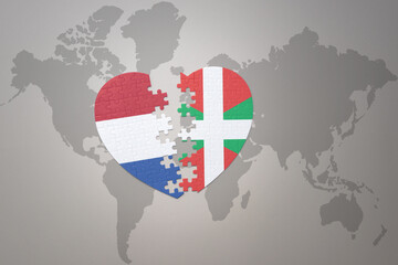 puzzle heart with the national flag of basque country and netherlands on a world map background.Concept.