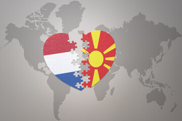 puzzle heart with the national flag of macedonia and netherlands on a world map background.Concept.