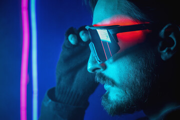 Serious man in the glasses in the neon lights close up portrait. Side view.