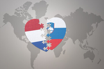 puzzle heart with the national flag of slovenia and netherlands on a world map background.Concept.