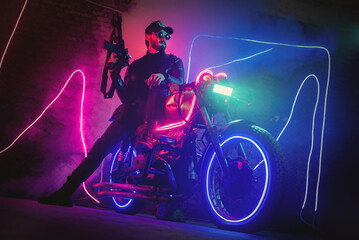 Plakat A special force agent with a rifle is hiding behind a futuristic motorbike and shooting. Cyberpunk concept.