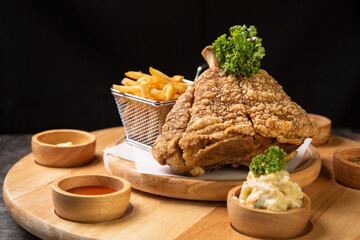 Pork knuckle Served with french fries and mashed potatoes on wooden cutting board