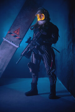 Spaceman or star trooper in the helmet and with rifle in the blue smoke. Science fiction concept.