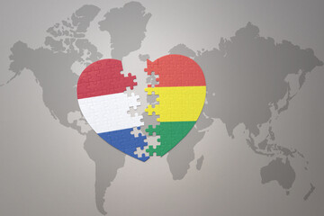 puzzle heart with the national flag of bolivia and netherlands on a world map background.Concept.