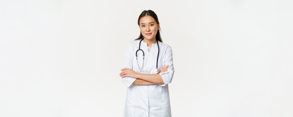 Image of confident female doctor, intern with stethoscope and medical robe, cross arms like professional, looking confident at camera, white background