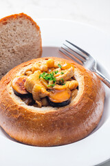 stew with pork meat, chickpeas and sausge in loaf of bread