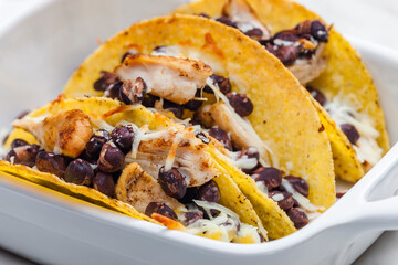 tacos filled with grilled chicken meat, red beans and grated cheese
