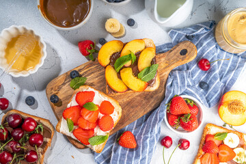 American European summer breakfast sandwiches, toasts with peanut butter, chocolate and cream cheese with berry and fruits, top view flatlay on kitchen table