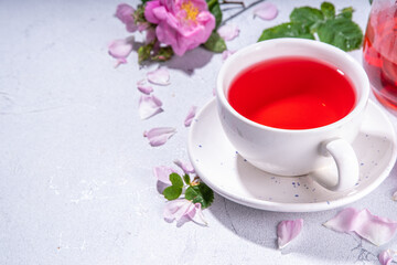 Rose buds tea, organic floral herbal hot tea drink with fresh rose flowers, in tea pot and cup, copy space