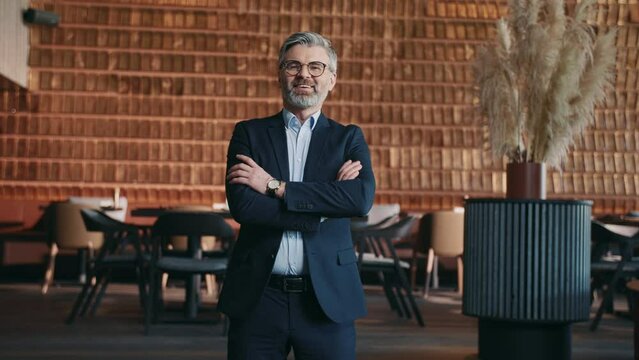Portrait of handsome successful male bar owner looking to camera and smiling. Middle-aged man in suit with arms folded across chest. Day, working day, occupation, profession. Wealthy, formal, indoor