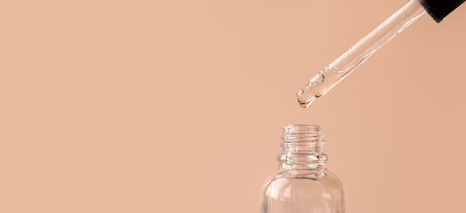Pipette with transparent fluid hyaluronic acid or serum. Cosmetics, science and healthcare concept closeup. Dose of serum or retinol falls in a bottle. Front view. Beauty product presentation, macro