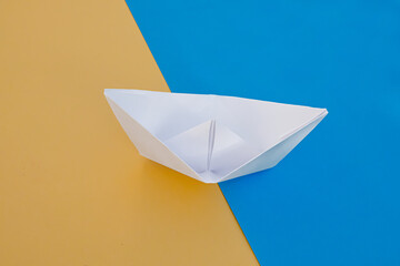 decorative paper ship on a blue-yellow background in the color of the flag of ukraine
