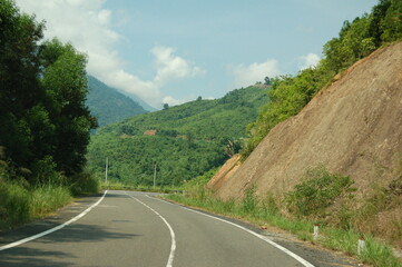 Fototapeta na wymiar An asphalt road passes through a mountain pass among the jungle.