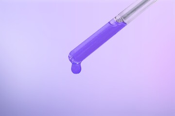 Glass lab dropper with a drop hanging from it on violet background, Abstract cosmetic ingredients...