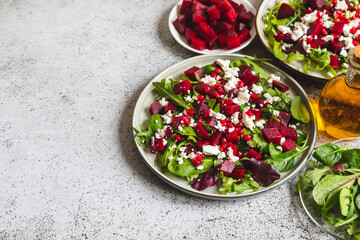 Arugula, Beet and cheese salad with pomegranate and dressing on plate on grey stone kitchen table background, place for text, top view