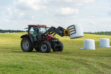 Farmer load hay bales to trailer.