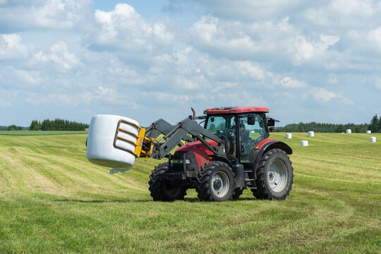 Farmer load hay bales to trailer.