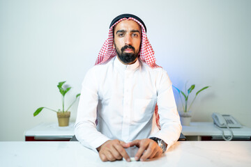 Arab Saudi man in office working in business corporate background using laptop or phone in a...