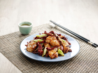 Stir-fried Gong Bao Chicken Fillet with chopsticks served in a dish isolated on mat side view on grey background