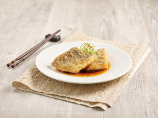 Crispy fried Flounder with Superior Soy Sauce with chopsticks served in a dish isolated on mat side view on grey background