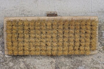 one old wooden clothing brush with brown plastic bristles on a gray table