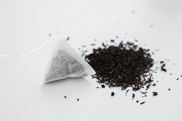 Tea bag on a white background. Tea bag on a pile of loose tea. Fast and convenient way to brew tea.