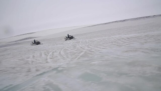 Aroup of tourists riding snowmobiles with a guide at Vatnajokull glacier in Iceland. Active sport, recreation, lifestyle.