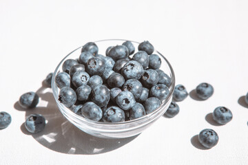 Blue blueberry in bowl and heap of berries on white, organic summer food
