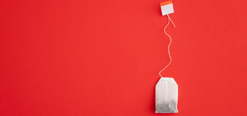 Tea bag with label on red background, space for text
