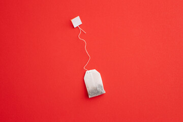 Tea bag with label on red background, space for text - Powered by Adobe