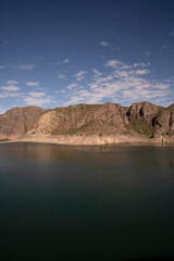 View of the lake and rocky hills in the desert under a deep blue sky.
