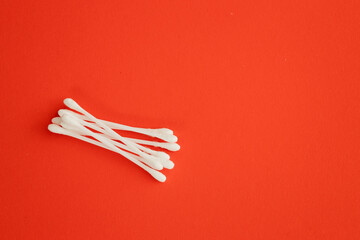 Obraz na płótnie Canvas Cotton ear sticks for personal hygiene on red background. Healthcare tools.