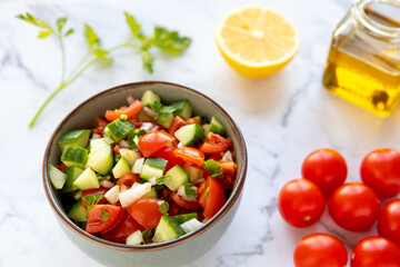 Tomato and cucumber salad. Fresh vegetable cut in cubes with lemon juice mixed in bowl.