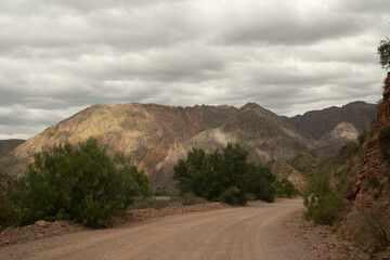 Driving along the empty desert route across the rocky mountains under a cloudy sky.
