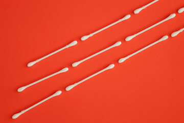 Cotton ear sticks for personal hygiene on red background. Healthcare tools.