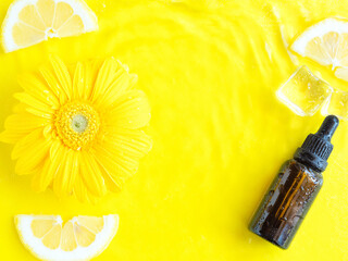 Dark glass essential oil, vitamin C serum on yellow background
