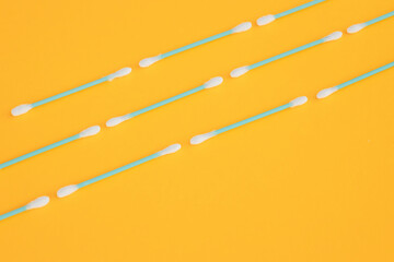 Flat lay composition with cotton swabs on yellow background. Top view ear sticks