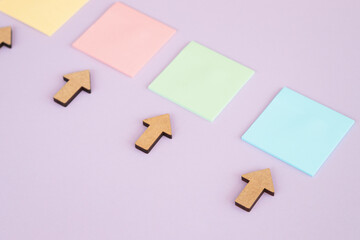 Colored square sticky notes and arrows on colorful background, top view.