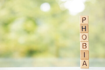 Phobia word is written on wooden cubes on a green summer background Closeup of wooden elements